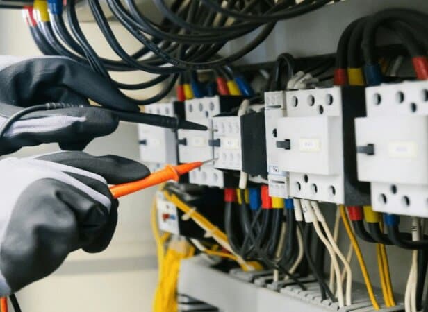 Elektroprüfer bei der Messung mit digitalem Multimeter am Arbeitsplatz